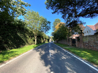 Fototapeta na wymiar Looking along, Stang Lane, with trees, and houses, on a hot summers day in, Farnham, Harrogate, UK