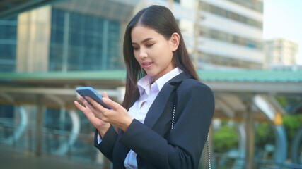 A young business woman wearing black suit is using smart phone , in the city, Business Lifestyle Concept..