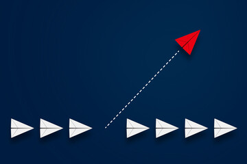 同じ方向へ向かう列から、一つ別方向へ抜け出した赤い紙飛行機。新しいアイデア・ビジネス、創造性、ソリューションのビジネスコンセプト