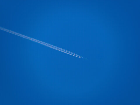 Beautiful picture of white plane flying with trail in blue sky