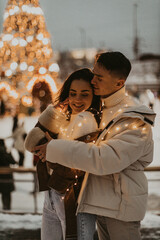 Young romantic couple in love outdoors in winter before Christmas.  Two lovers are hugging and kissing in Saint Valentine's Day.
