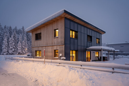 sustainable solar thermal heated house with collector and wood facade in the evening in winter with lots of fresh snow