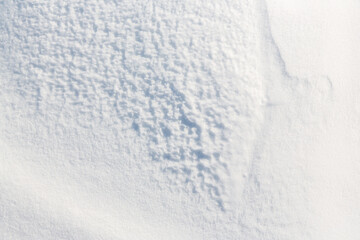 Beautiful winter background with snowy ground. Natural snow texture. Wind sculpted patterns on snow surface.