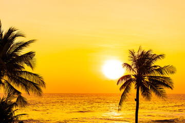 Naklejka na ściany i meble Beautiful tropical beach sea ocean at sunrise or sunset with palm tree