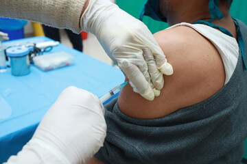 Fototapeta premium a close up photo of an intra muscular covid vaccine being given in arm of a patient by a doctor with gloved hand with selective focus on arm