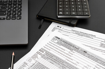 Tax forms with laptop, notepad and calculator on black office desk. Filing tax form.