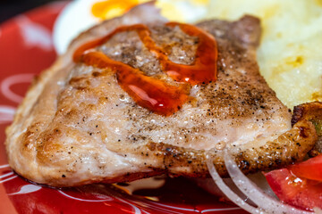 Delicious fried meat drenched in ketchup on a white plate