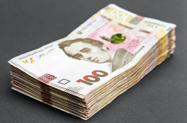 Stack of ukrainian one hundred bills on grey background.