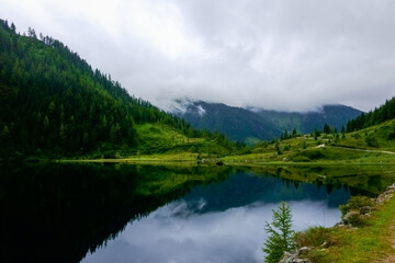 Naklejka na ściany i meble reflection in a mountain lake in the mountains with dense clouds