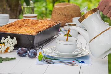 Plum cake served with coffee served in summer garden