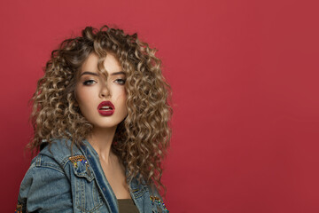 Attractive fashion model woman with curly hair on red background