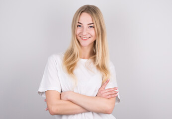 Fototapeta premium Happy cheerful young blond teenager with arms crossed looking at camera with joyful and charming smile.
