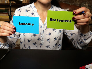 BusinessWoman holding a blank business cards. Business concept about Income Statement with phrase...