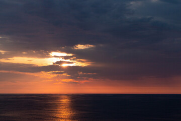 Fototapeta na wymiar beautiful orange sunset over the dark sea wit an orange line of reflection. Horizontal picture.