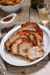Sliced into slices baked turkey breast underneath sour- sweet   sauce at the dinner table
