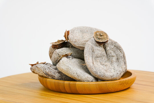 Dried persimmon on white background.  Naturally, sweet dry kinglet fruit on wooden bowl. Free space for text. Product for sale.  Studio photo.