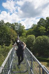 Young sporty woman crosses the suspension bridge