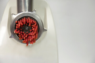 Electric meat grinder grinds raw red meat into mince