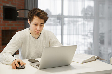 A man working on a laptop at home at bright kitchen