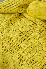 Yellow pattern crocheted.Knitted dress lies on the table with threads.