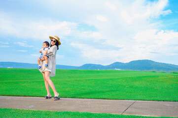 Mother and baby boy playing on the grass summer background with mum and child