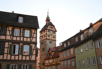 Historical half-timbered houses and the Josenturm tower in the old town of Schwäbisch Hall, Germany under a clear blue sky.