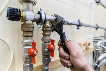 A plumber installs equipment into a home heating system. Stainless steel pipe assembly process and brass valve assembly. Cropped frame. Beyond recognition