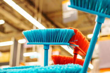 Plastic brushes of different colors. Broom for cleaning the house in a DIY store. Trade in...