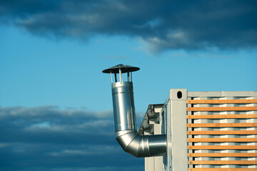 Stainless steel chimney on a metal container. Fragment of a change house with a branch pipe for...