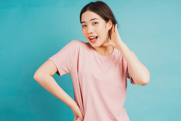 Portrait of young girl listening to conversation on blue background