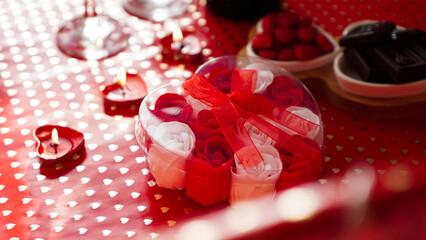 Valentines day gift on a red festive background. A lot of red and white roses in a heart-shaped package, tied with a red ribbon. The concept of dinner