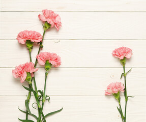 Pink carnation flowers on on white rustic wood.