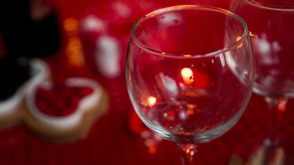 Empty wine glass on love dinner. Candles for valentines day, table with festive red background.