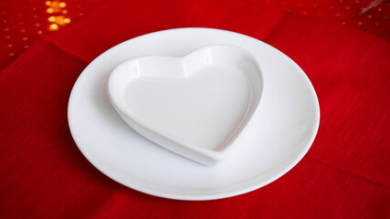 Heart shaped white plate on red background