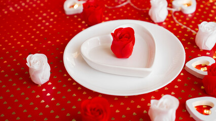 Obraz na płótnie Canvas Place setting in red and white - for Valentine or other event. White plate in the shape of a heart with a decor of roses on a red background
