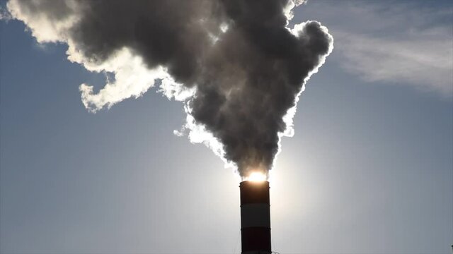 Dark hot smoke coming out of an industrial chimney of a chemical plant. Air pollution and global warming	