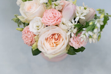 Delicate bouquet of flowers in a hat box on a light background.