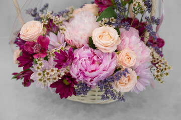 Floral arrangement of delicate peonies and other flowers, on a light background.