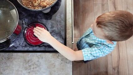 Curious toddler burns hand with hot electric stove in kitchen at home