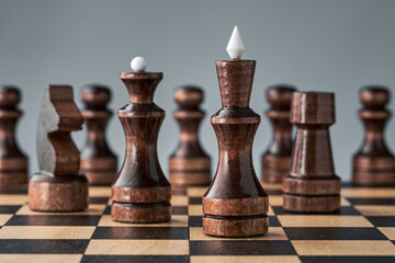 Wooden chess pieces on a chessboard, black king and queen in the foreground, concept, strategy, planning and decision making. The concept of leadership and teamwork for success