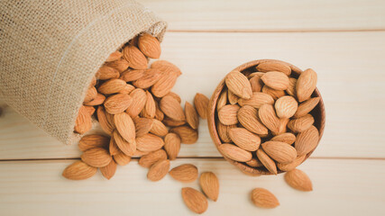 Almonds raw peeled in brown wooden bowl with bag on wooden table background.Healthy food Concept.