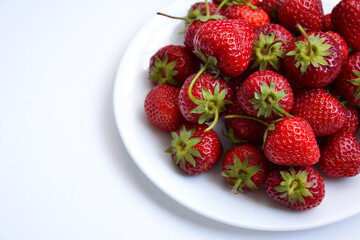 Strawberries on white plate. Freshly picked strawberry. Organic berries on white background. Village garden harvest.
