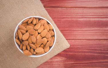 Almonds raw peeled in white porcelain bowl on wooden table background.Healthy food Concept.
