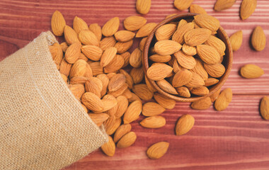 Almonds raw peeled in brown wooden bowl with bag on wooden table background.Healthy food Concept.