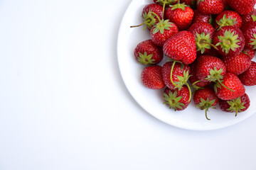 Strawberries on white plate. Freshly picked strawberry. Organic berries on white background. Village garden harvest.