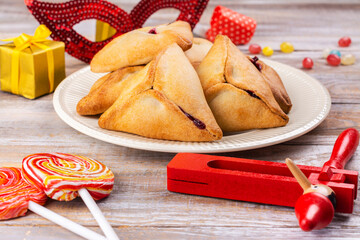 Purim celebration background. Jewish carnival. Mask, traditional jewish hamantaschen cookies cakes, rattle noisemaker and other carnival accessories on light background