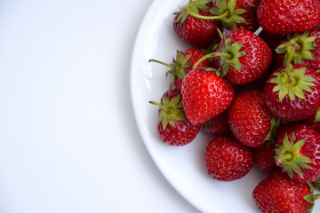 Strawberries on white plate. Freshly picked strawberry. Organic berries on white background. Village garden harvest.