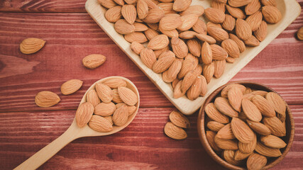 Almonds pour from wood spoon with brown wooden bowl on wooden table background.Healthy food Concept.