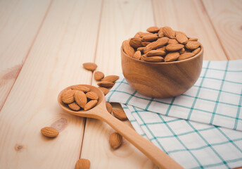 Almonds in brown wooden bowl with wooden spoon on wooden table background.Healthy food Concept