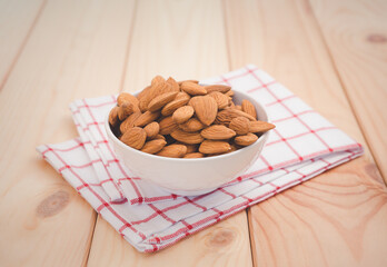 Almonds in white porcelain bowl on wooden table background.Healthy food Concept.